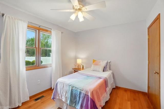 bedroom featuring a ceiling fan, baseboards, light wood-type flooring, and visible vents