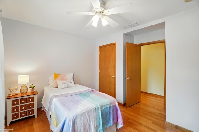 bedroom with light wood finished floors, a closet, ceiling fan, and visible vents