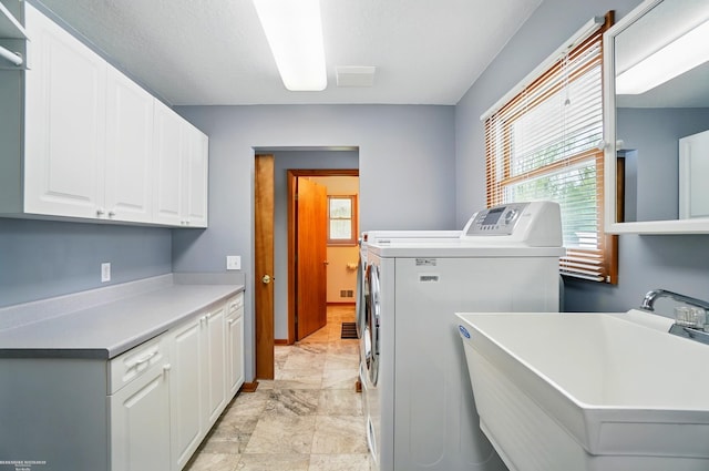 clothes washing area with a sink, cabinet space, baseboards, and washer and dryer