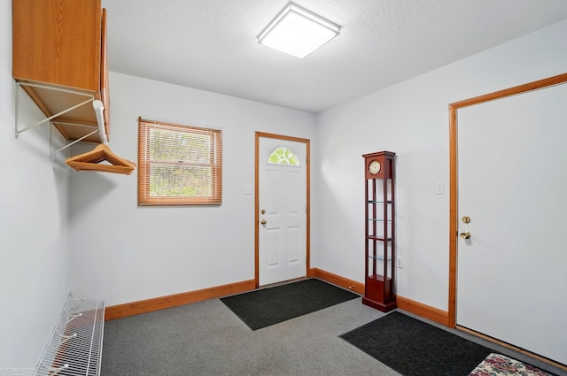 foyer featuring baseboards and carpet flooring