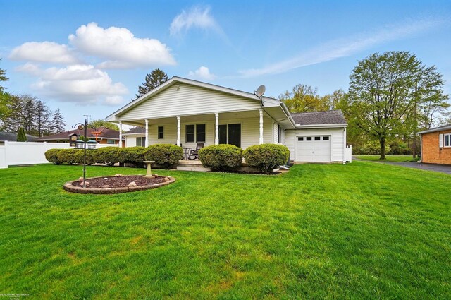 view of front of property featuring covered porch, a front lawn, an attached garage, and fence