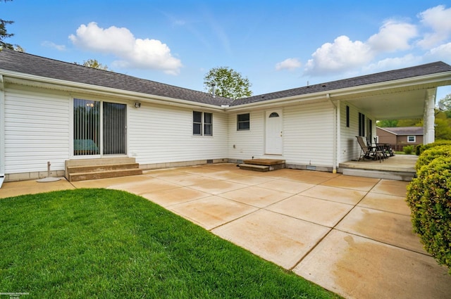 rear view of house featuring entry steps, a patio area, and a lawn