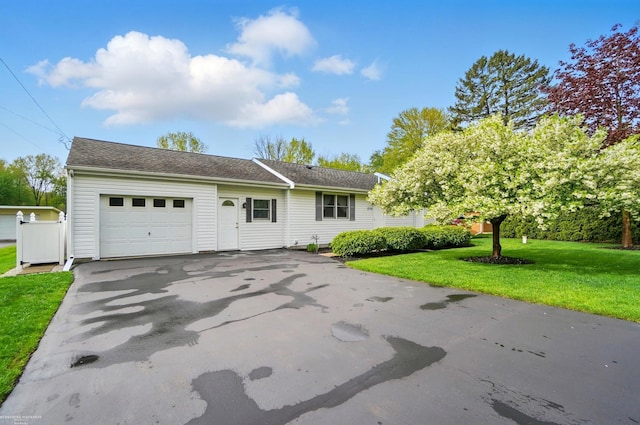 single story home featuring a front yard, aphalt driveway, and an attached garage
