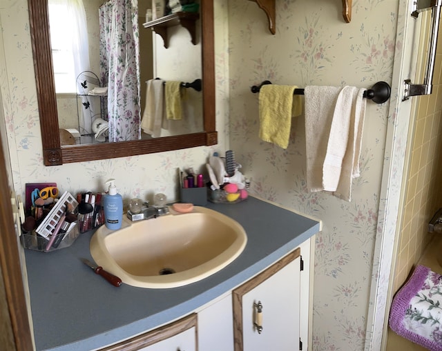 bathroom with vanity and wallpapered walls