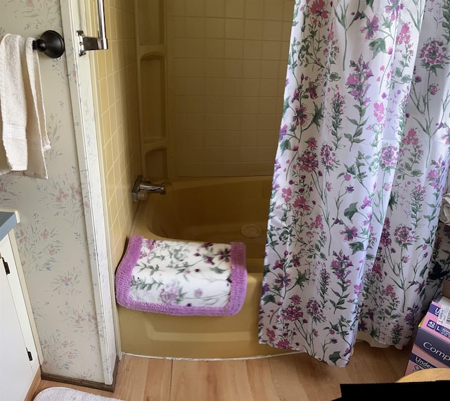 full bath featuring shower / bath combo with shower curtain, wallpapered walls, and wood finished floors
