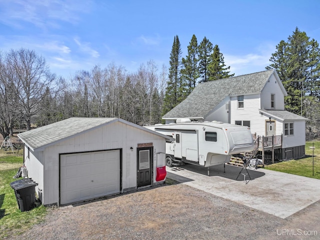 view of front of home with a shingled roof, an outbuilding, a wooden deck, and a detached garage