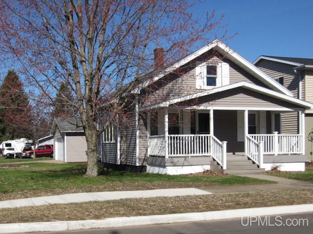 bungalow-style house featuring a chimney and covered porch