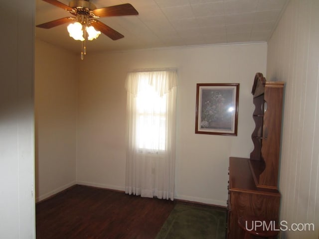 spare room featuring a ceiling fan, baseboards, ornamental molding, and wood finished floors