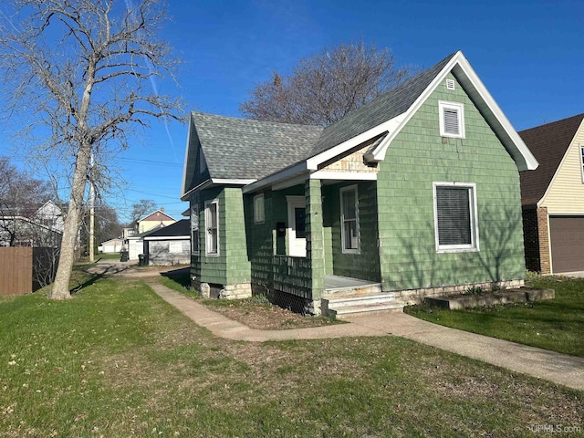 bungalow-style home featuring covered porch, a garage, a shingled roof, and a front yard