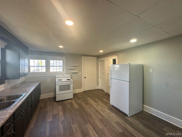 kitchen with a sink, white appliances, baseboards, and dark wood finished floors
