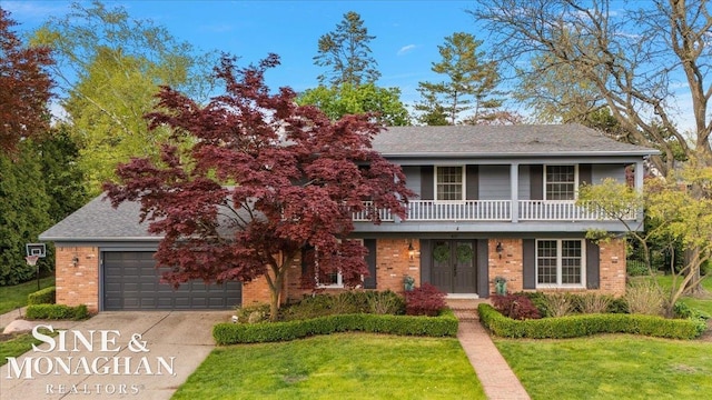 view of front of property featuring brick siding, a front lawn, concrete driveway, and a balcony