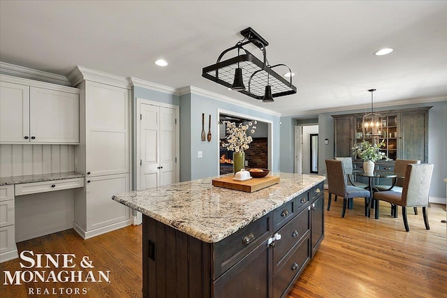 kitchen with a chandelier, white cabinetry, light wood-style floors, decorative light fixtures, and a center island