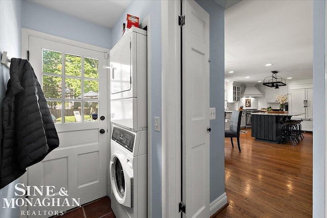 laundry area featuring estacked washer and dryer, recessed lighting, and dark wood-style floors