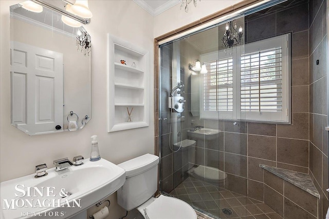 bathroom featuring ornamental molding, a stall shower, toilet, a sink, and built in shelves