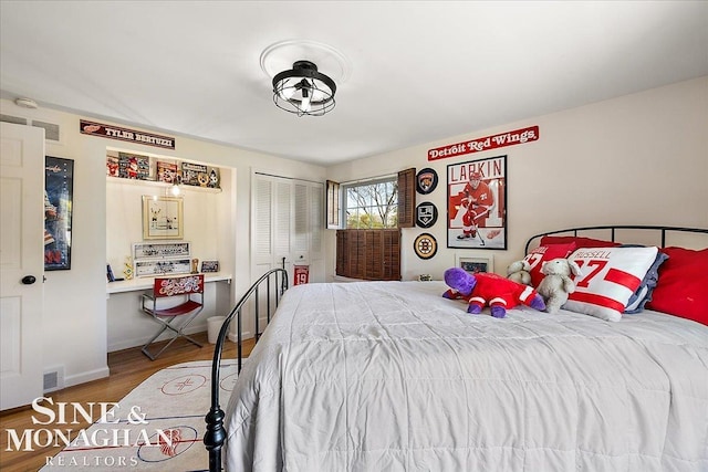 bedroom with wood finished floors, a closet, and baseboards
