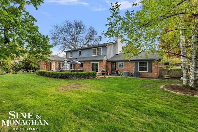 rear view of house featuring brick siding, central AC unit, a deck, and a chimney