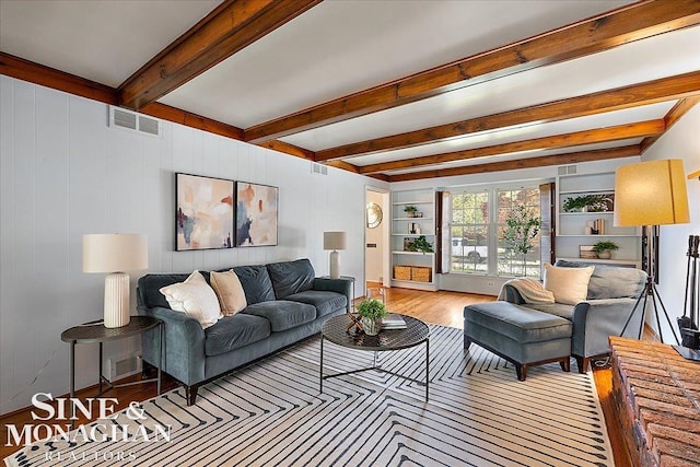 living area with wood finished floors and beam ceiling