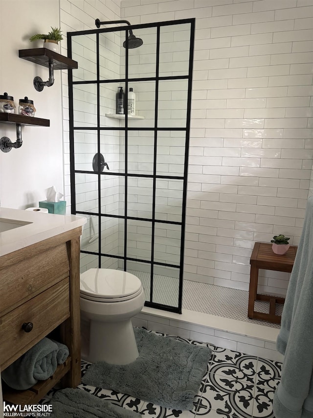 full bath with a tile shower, toilet, tile patterned flooring, and vanity
