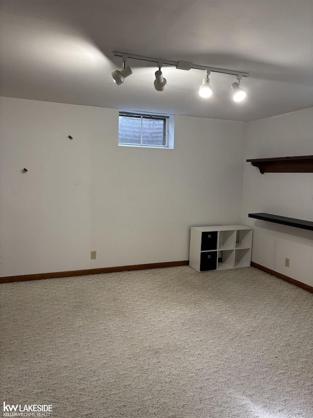 basement with rail lighting, carpet floors, and baseboards