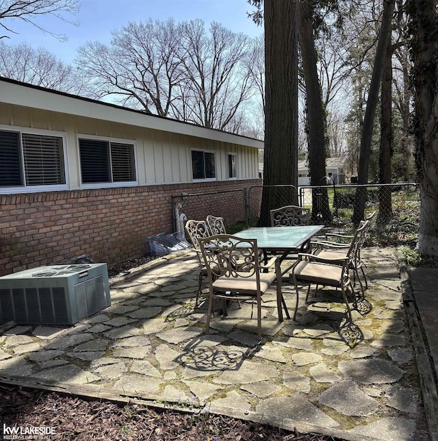 view of patio featuring cooling unit, outdoor dining space, and fence
