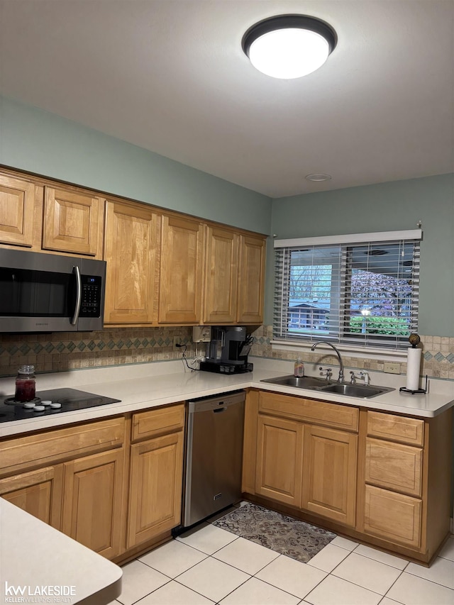 kitchen with stainless steel appliances, a sink, tasteful backsplash, light countertops, and light tile patterned floors