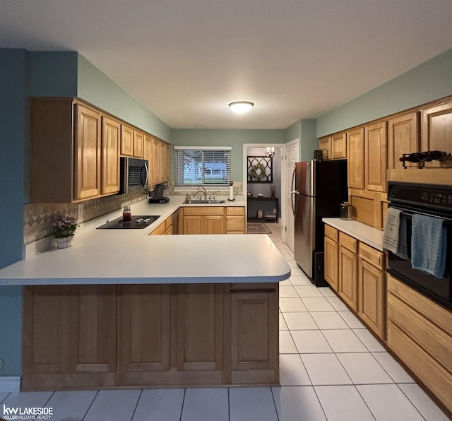 kitchen featuring black appliances, a sink, light countertops, decorative backsplash, and a peninsula