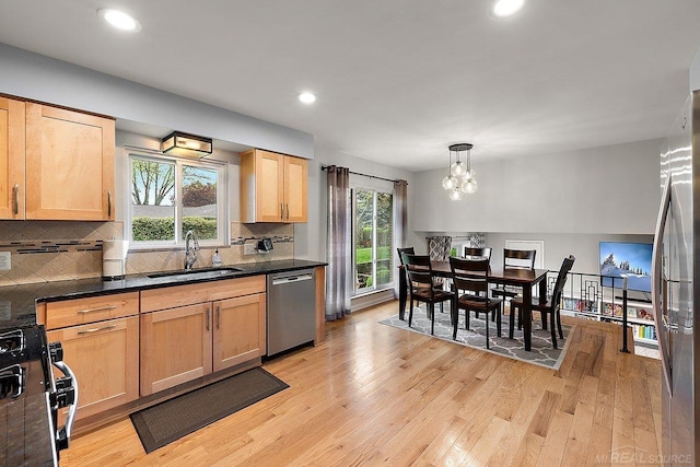 kitchen featuring a sink, appliances with stainless steel finishes, light brown cabinets, light wood-type flooring, and dark countertops