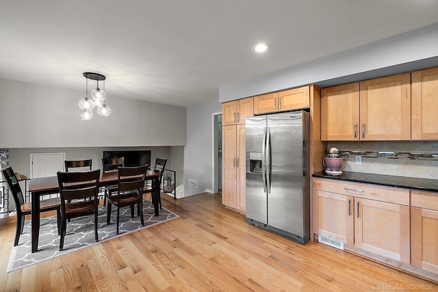 kitchen with stainless steel refrigerator with ice dispenser, light wood finished floors, decorative backsplash, dark countertops, and recessed lighting