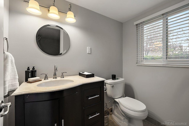 half bathroom featuring toilet, vanity, and baseboards