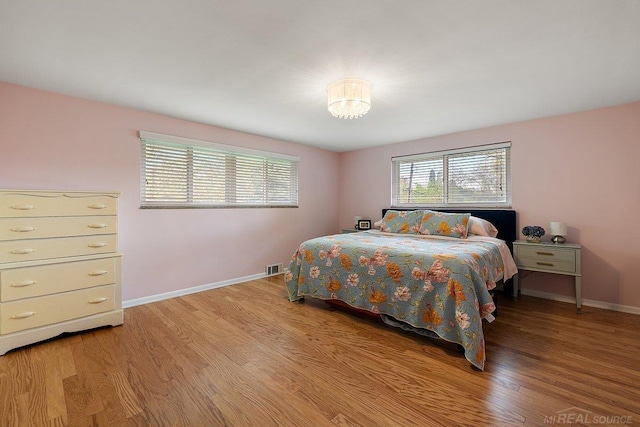 bedroom with baseboards, light wood finished floors, and a chandelier