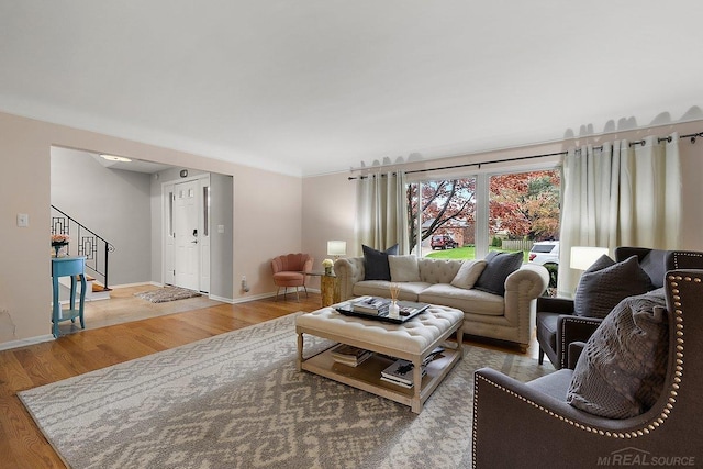 living room featuring wood finished floors, stairs, and baseboards