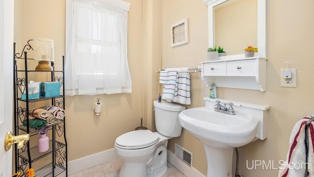 bathroom with baseboards, toilet, tile patterned floors, and a sink
