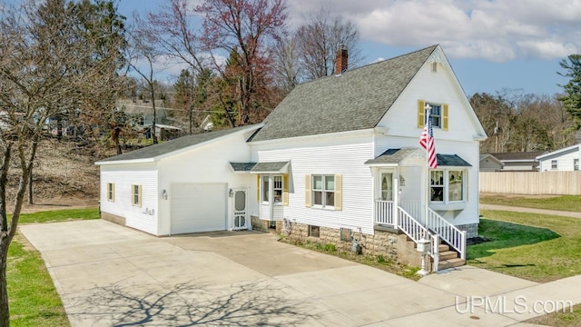 traditional-style house with an attached garage, concrete driveway, a shingled roof, and a chimney