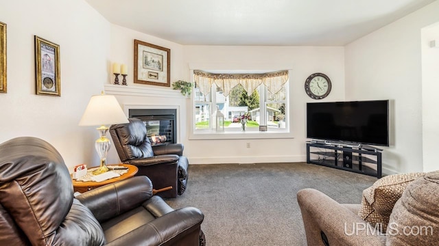 living room featuring dark colored carpet, a glass covered fireplace, and baseboards