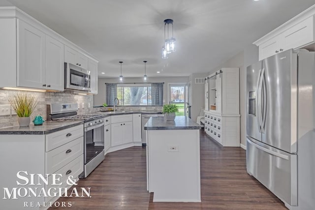 kitchen with stainless steel appliances, a center island, white cabinetry, and decorative backsplash