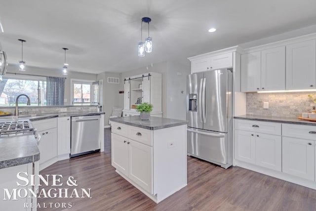 kitchen with stainless steel appliances, a sink, dark wood-type flooring, backsplash, and recessed lighting