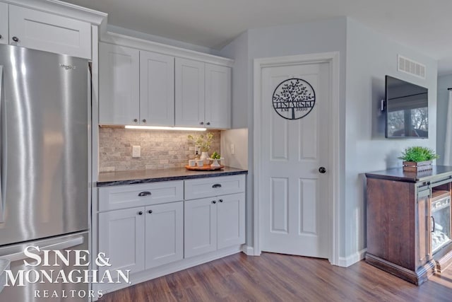 kitchen with freestanding refrigerator, dark wood-type flooring, white cabinets, and tasteful backsplash