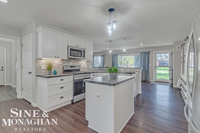 kitchen featuring stainless steel appliances, a peninsula, a kitchen island, tasteful backsplash, and dark wood-style floors