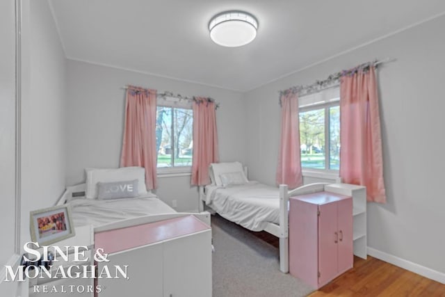 bedroom with multiple windows, light wood-type flooring, and baseboards