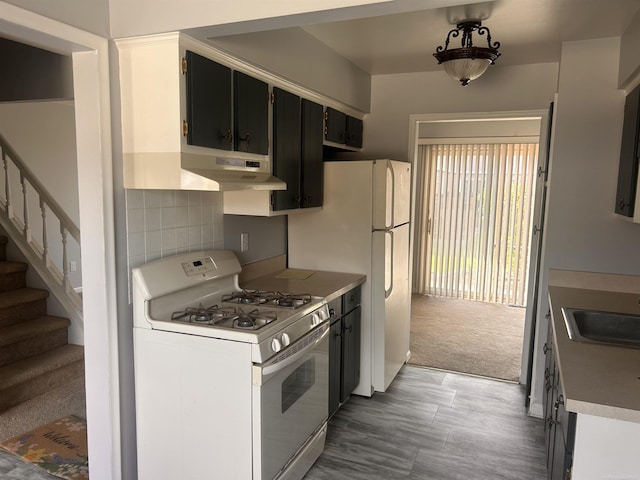 kitchen with white gas range oven, a sink, under cabinet range hood, decorative backsplash, and light countertops