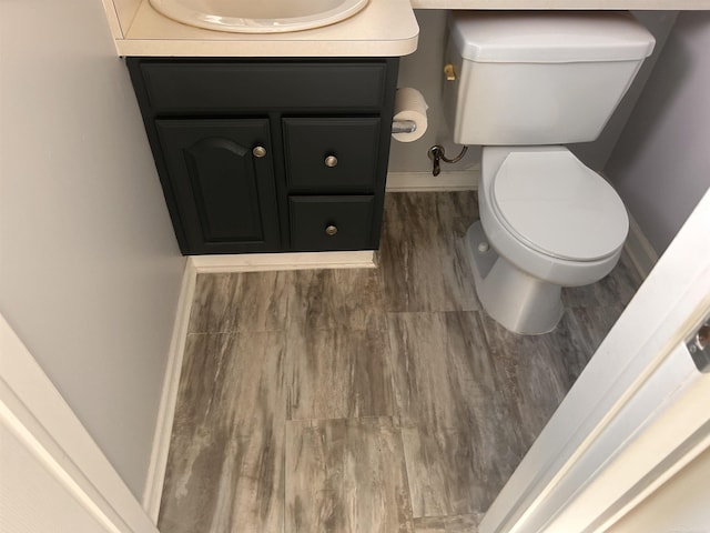 half bathroom featuring vanity, toilet, and baseboards