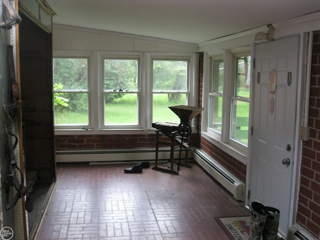 sunroom with brick patterned flooring, a baseboard radiator, and brick wall