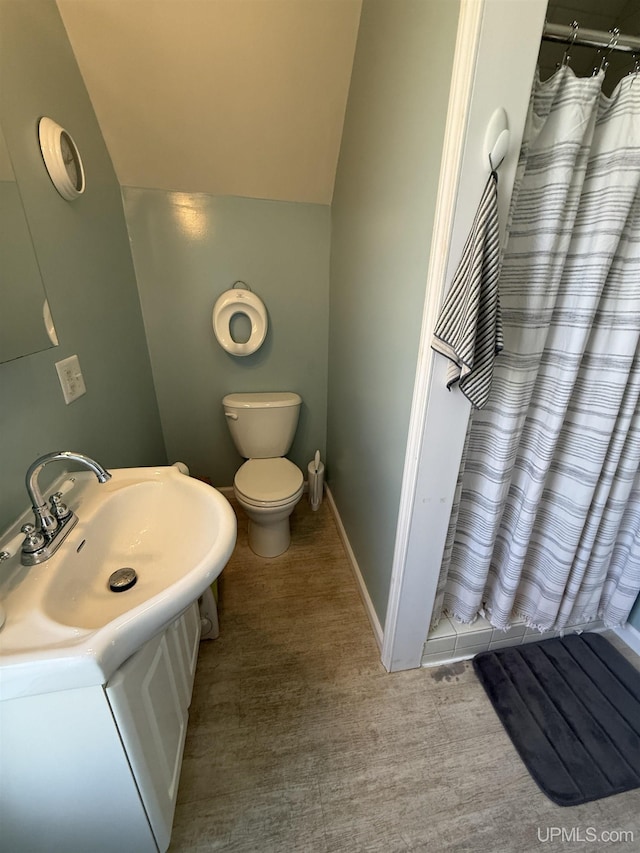 full bathroom featuring toilet, a shower with shower curtain, vanity, vaulted ceiling, and baseboards