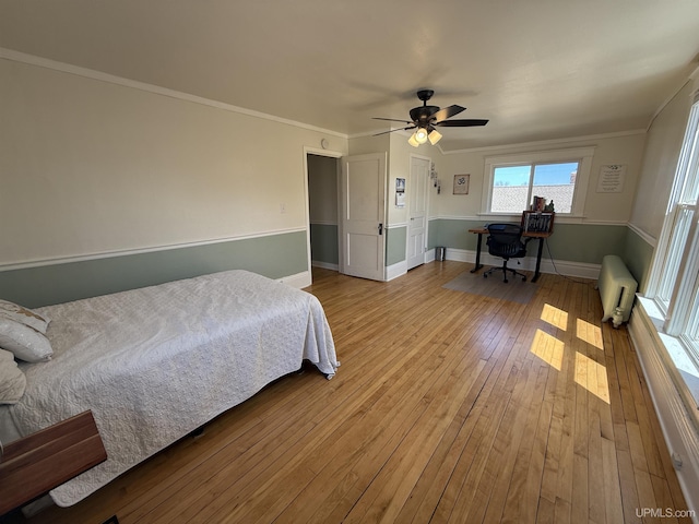 bedroom featuring hardwood / wood-style floors, an office area, baseboards, a ceiling fan, and crown molding