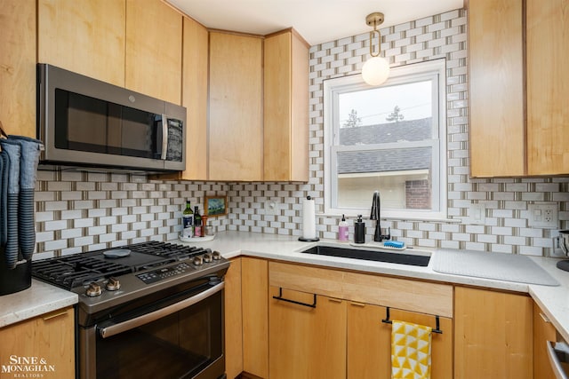 kitchen featuring stainless steel appliances, a sink, backsplash, light countertops, and light brown cabinets