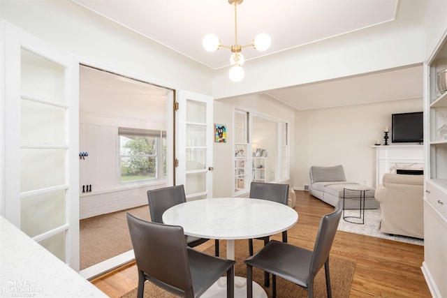 dining space with light wood-style flooring, a high end fireplace, and french doors