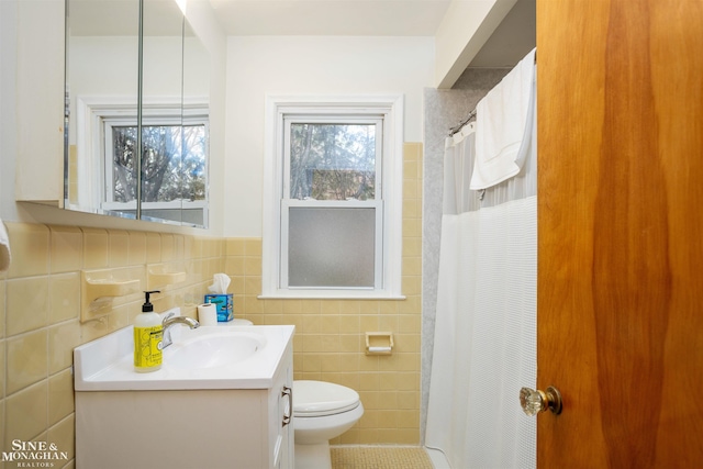 bathroom featuring tile walls, toilet, vanity, curtained shower, and a wainscoted wall