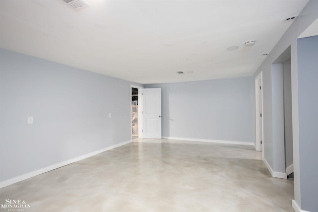 spare room with finished concrete flooring, baseboards, and a smoke detector