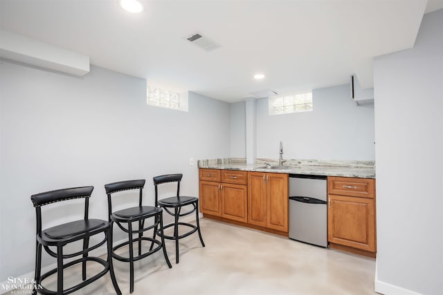 kitchen featuring fridge, a sink, brown cabinets, recessed lighting, and light stone countertops