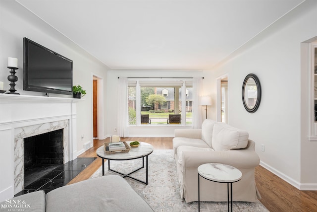 living room featuring a premium fireplace, baseboards, and wood finished floors